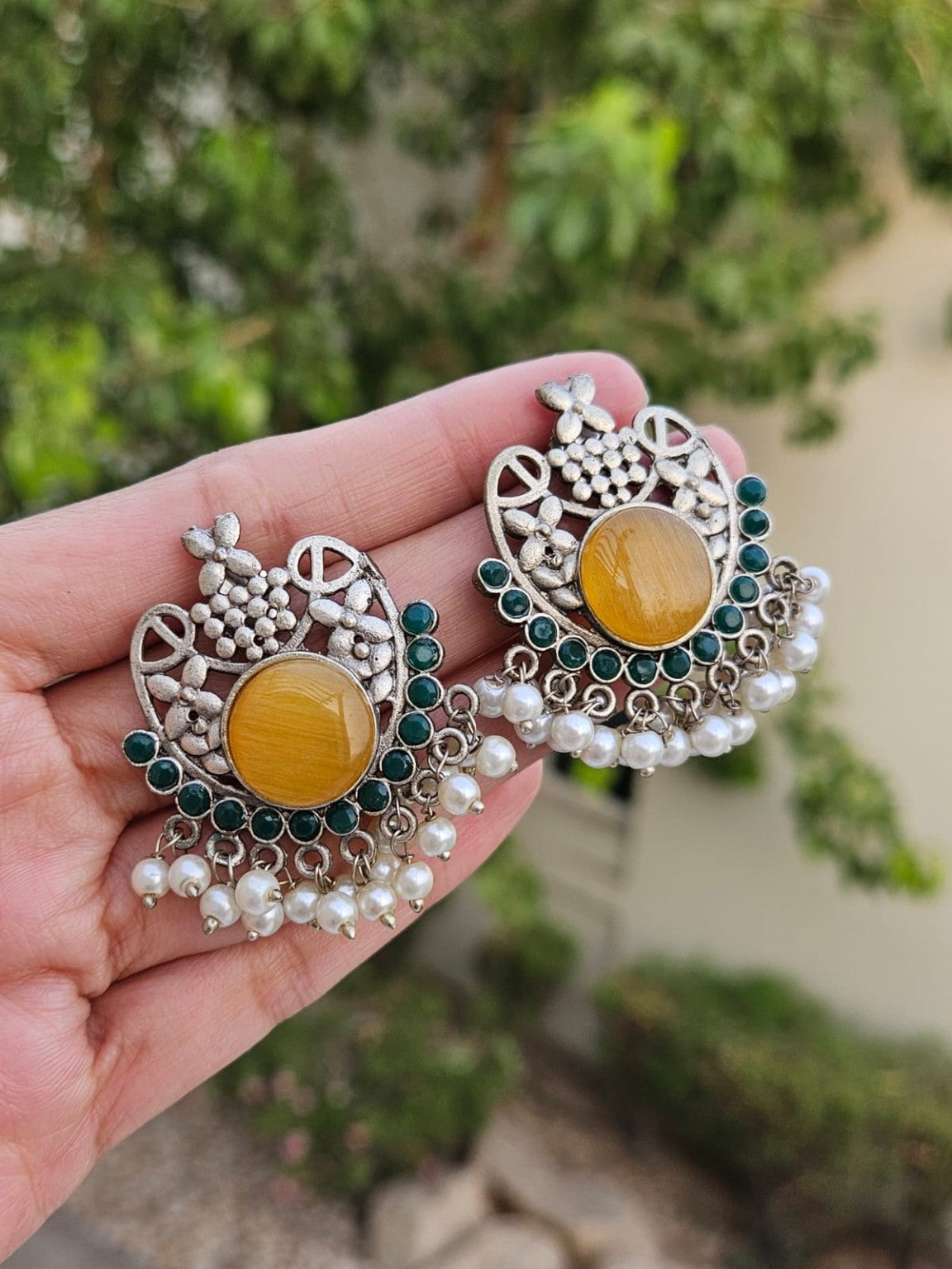 Yellow floral silver lookalike earrings with Mona Lisa stone and pearls in natural daylight