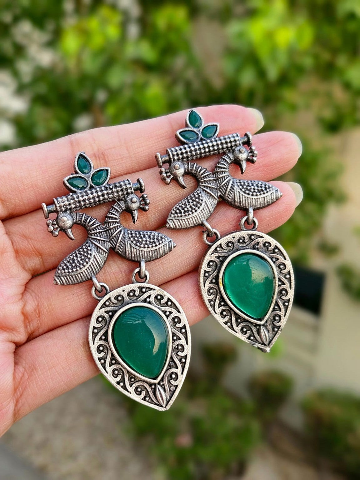 Green peacock Mona Lisa stone earrings in natural daylight