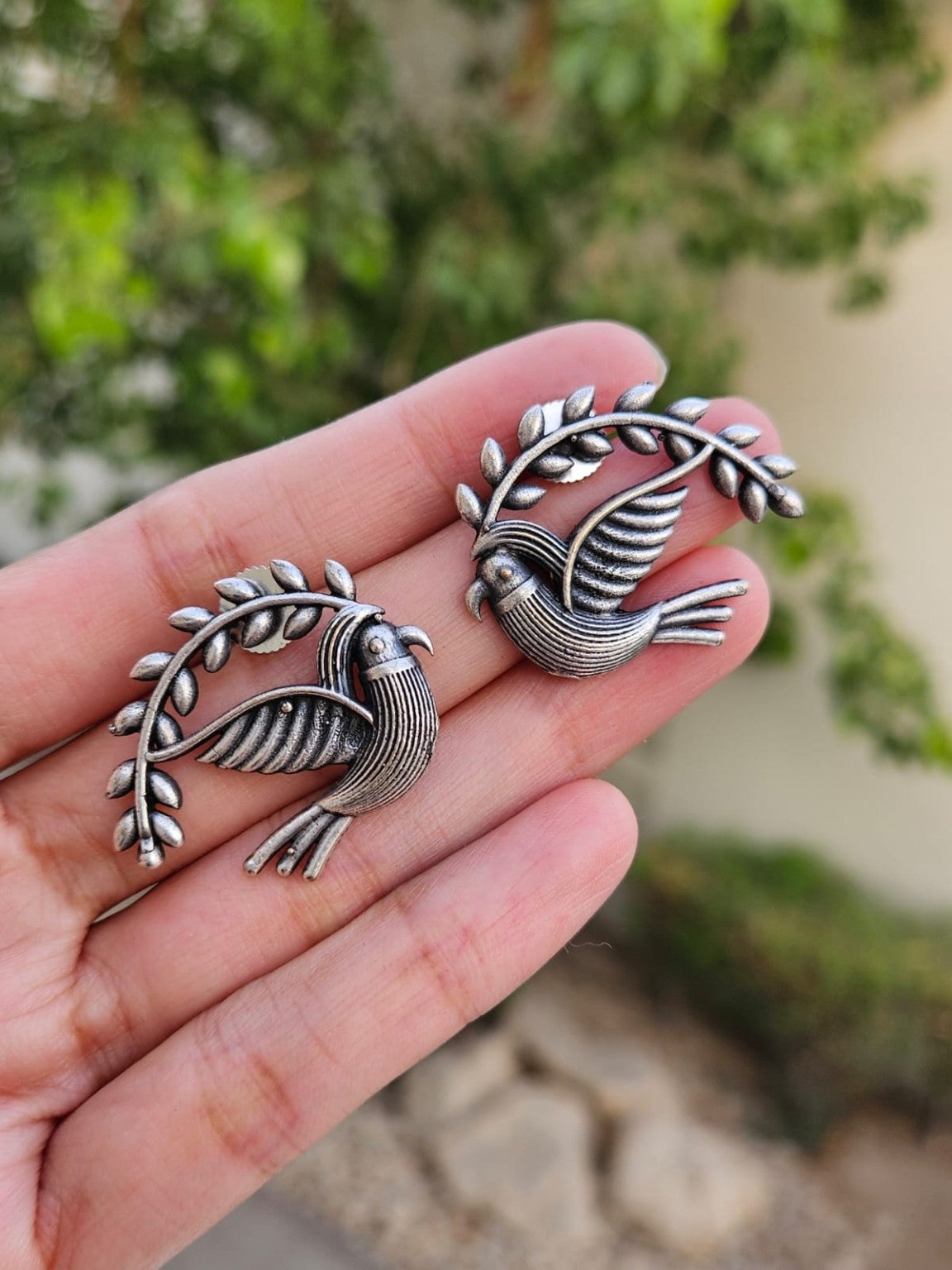 Silver lookalike bird earrings in natural daylight