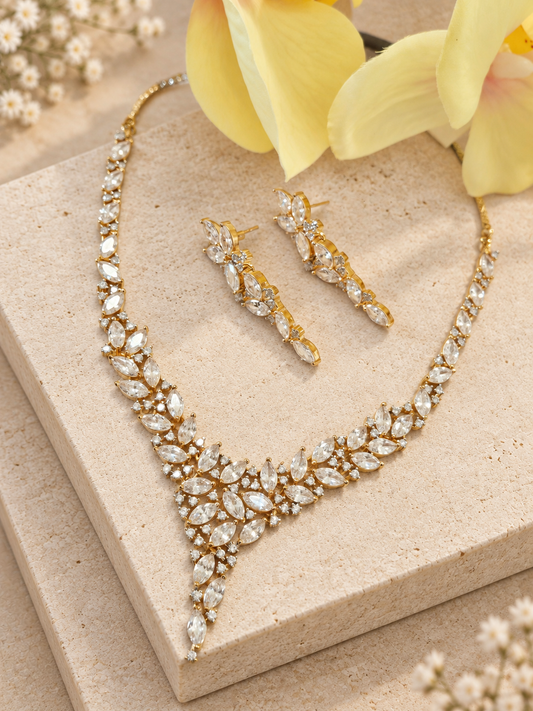 Gold-tone necklace and matching earrings with clear marquise stones and a pointed drop on beige square stones.