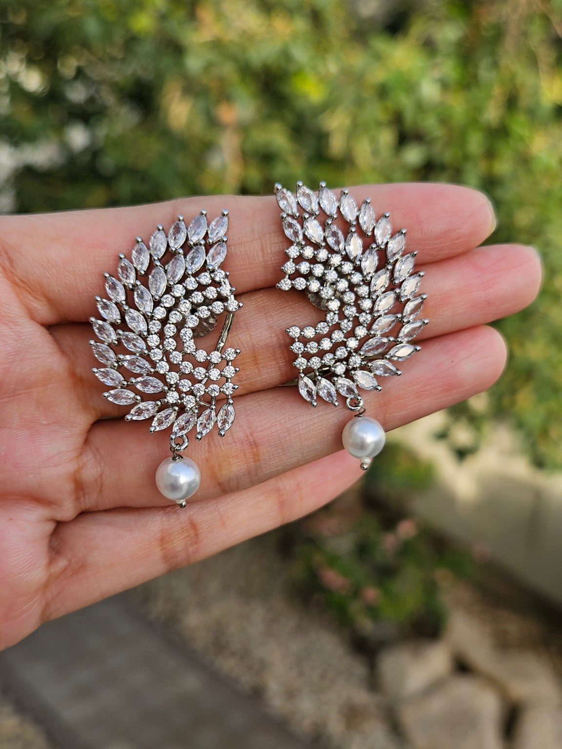 White CZ pearl drop rhodium plated statement earrings photographed in natural daylight