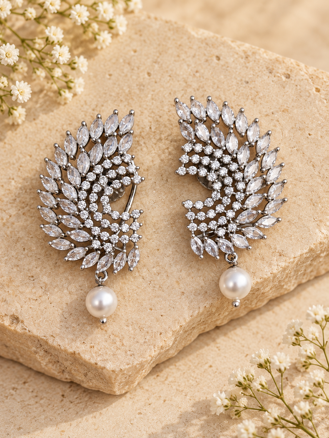 White CZ statement earrings with pearl drop and rhodium plating on beige stone background
