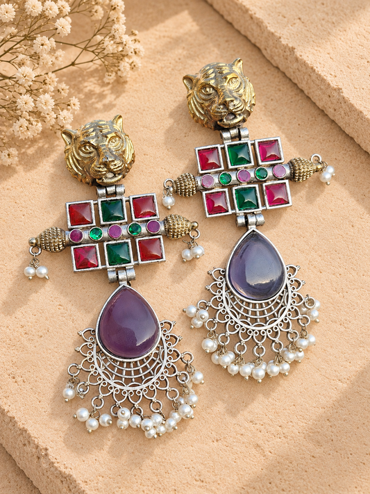 Dual-tone tiger-head earrings with purple Monalisa teardrops, coloured accents and white bead clusters on beige stone.