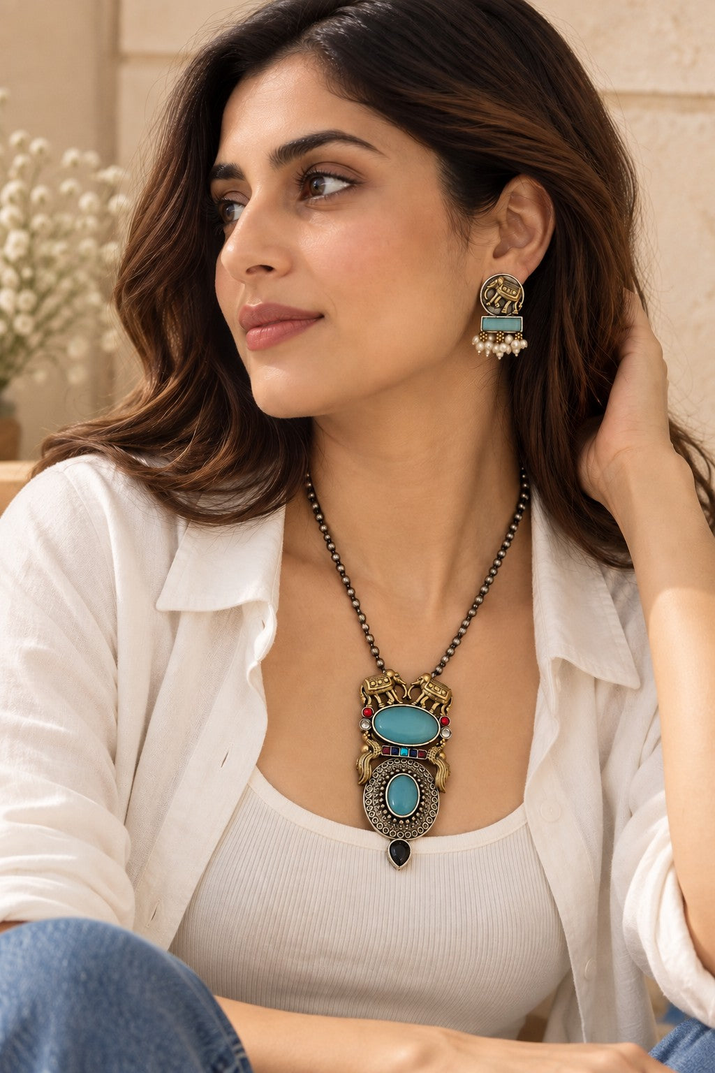Model wearing Aara dual tone elephant pendant necklace and matching earrings with a casual western outfit