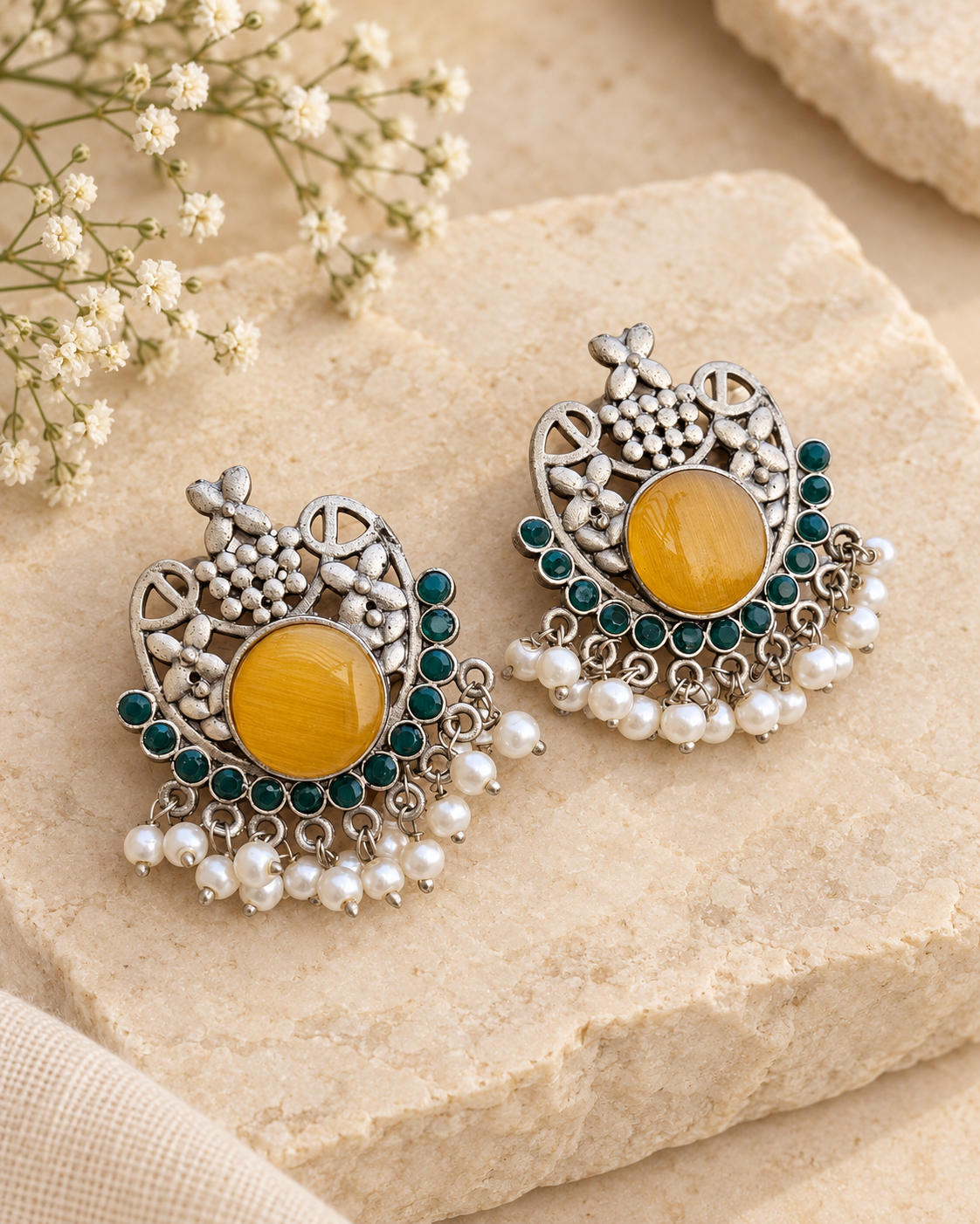 Yellow floral silver lookalike earrings with Mona Lisa stone and pearls on beige stone background