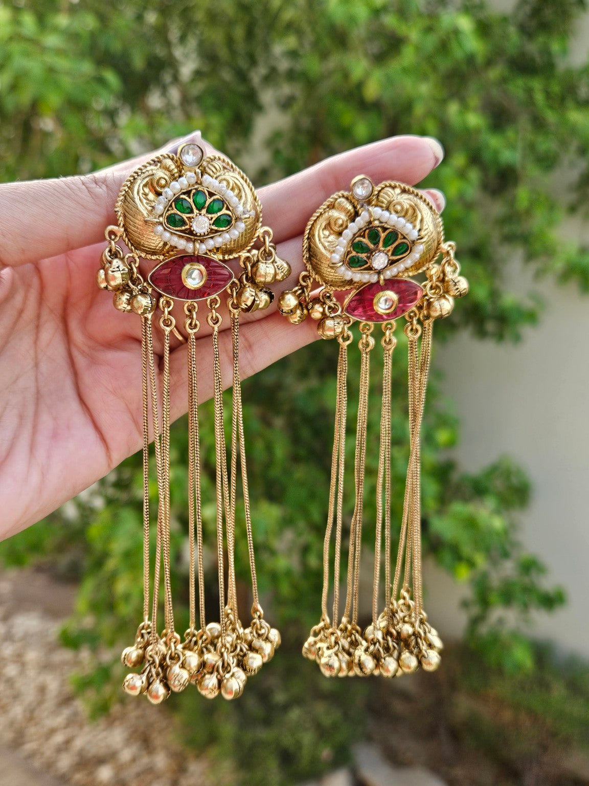 Gold tone long tassel statement earrings in natural daylight