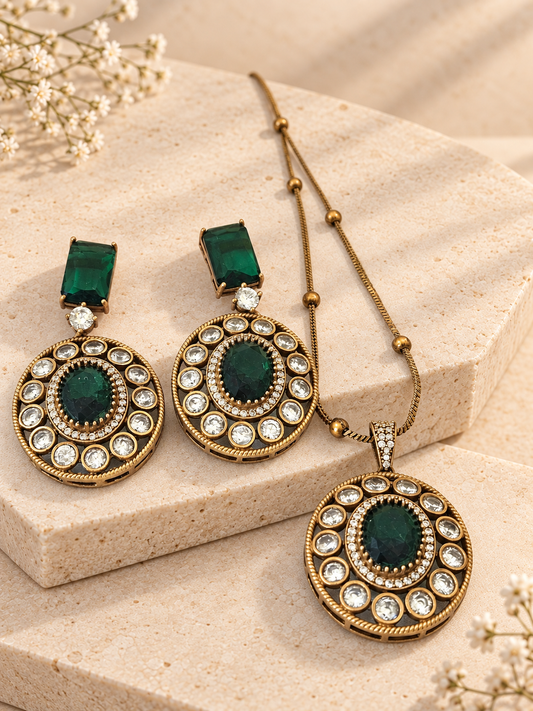 Green oval Polki pendant necklace with matching drop earrings on two beige square stone slabs.