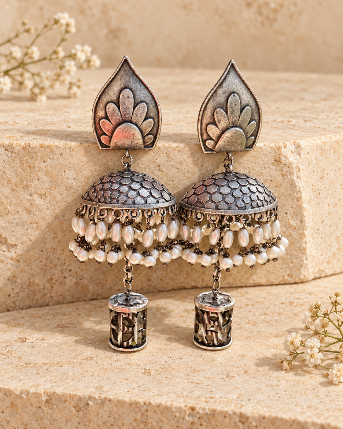 Leaf top oxidized silver lookalike jhumka earrings on beige stone background