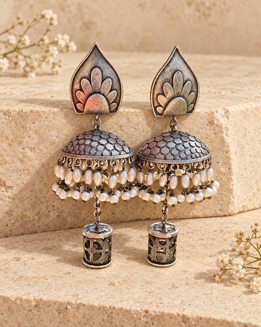 Leaf top oxidized silver lookalike jhumka earrings on beige stone background