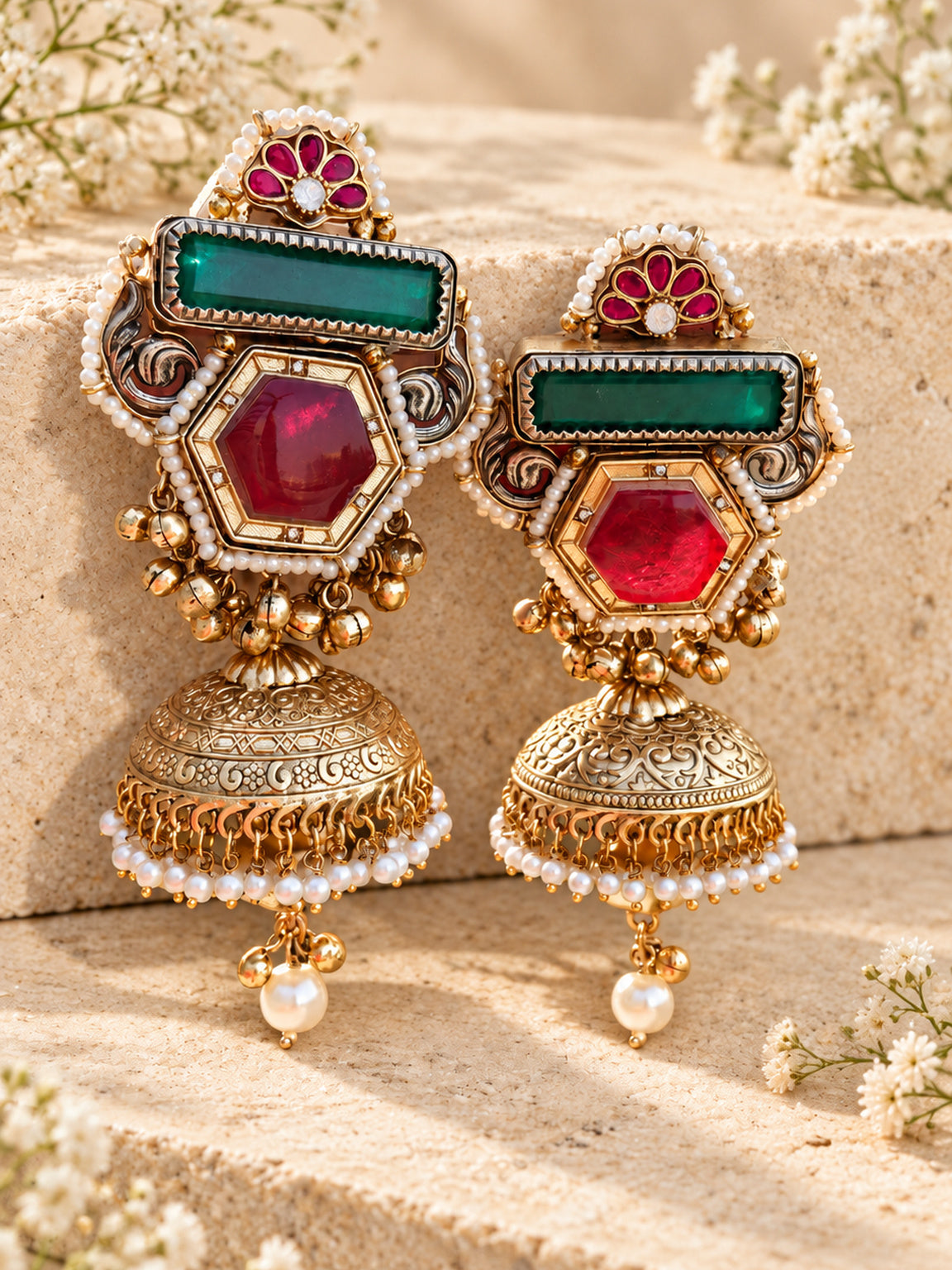 Luxury antique gold doublet stone jhumka earrings with pearl and ghungroo detailing on beige stone background