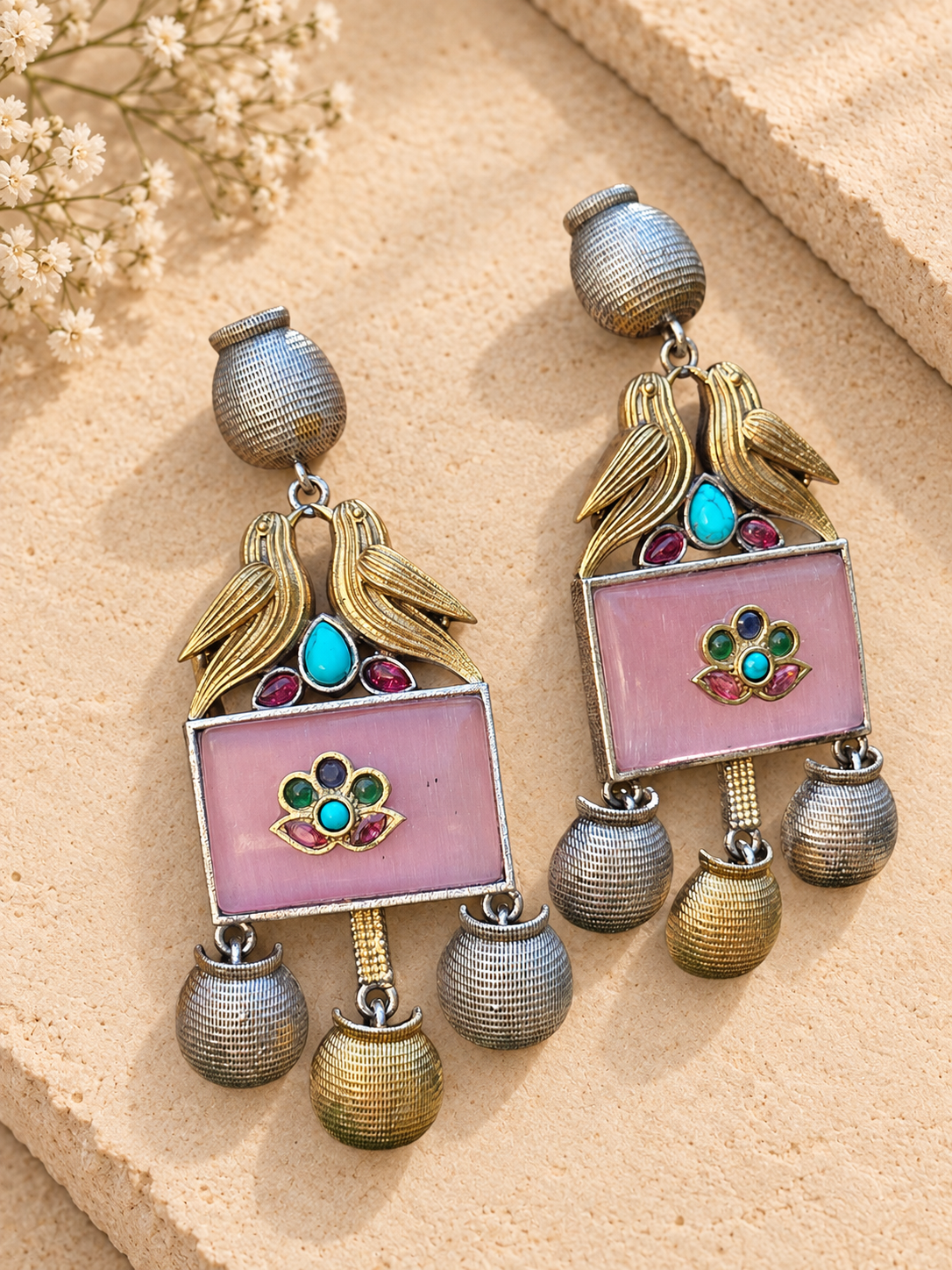 Dual-tone bird earrings with pink rectangular stones and ribbed metal drops on beige stone.