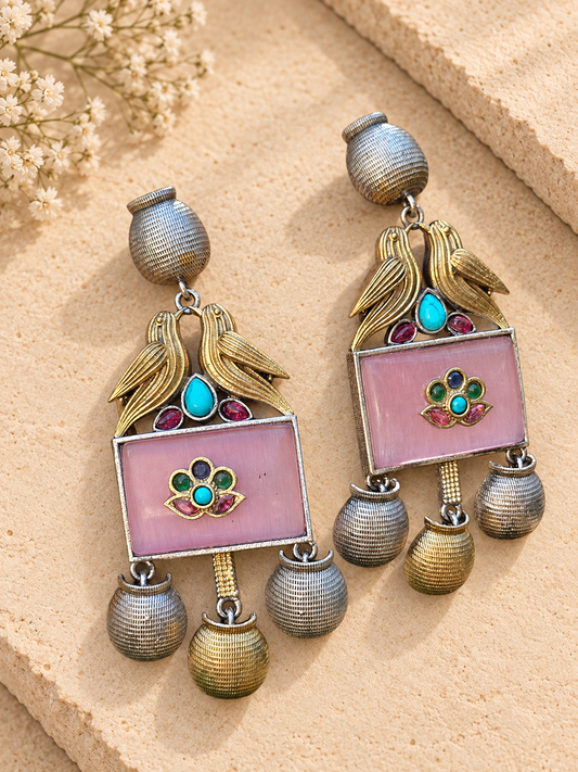 Dual-tone bird earrings with pink rectangular stones and ribbed metal drops on beige stone.