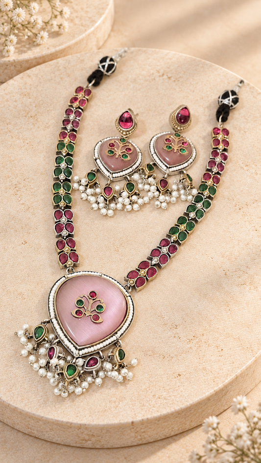 Pink Monalisa necklace and matching earrings with green and pink accents and white bead clusters on creamy beige stone.