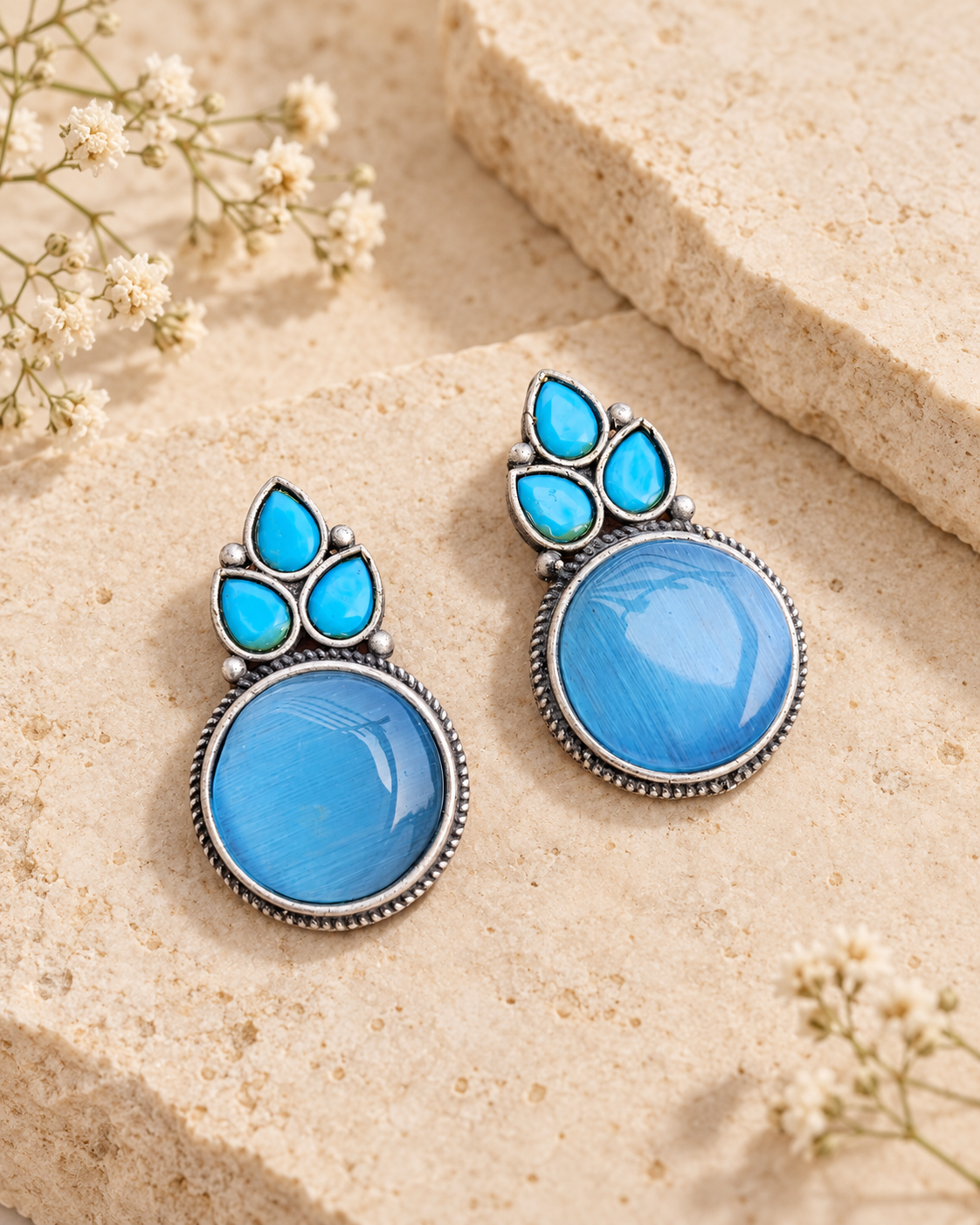 Blue Mona Lisa stone stud earrings on beige stone background