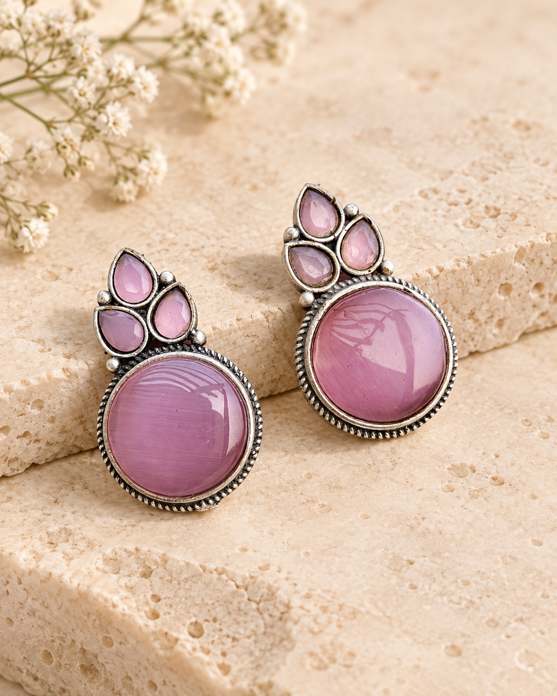 Pink Mona Lisa stone stud earrings on beige stone background