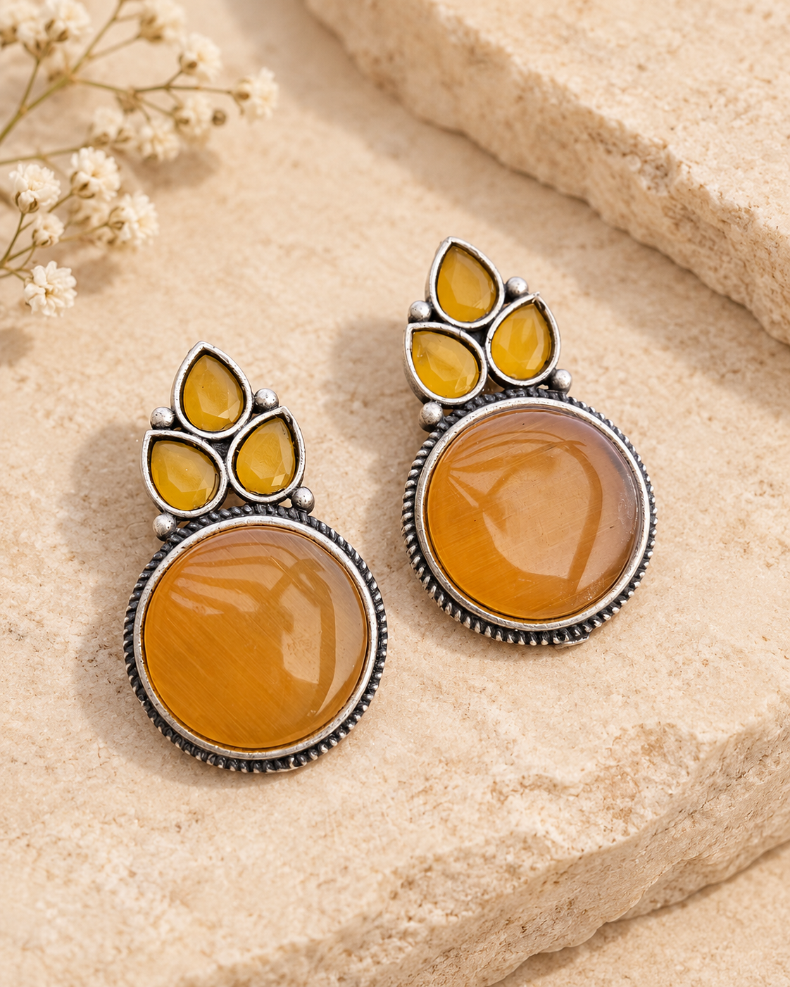 Yellow Mona Lisa stone stud earrings on beige stone background