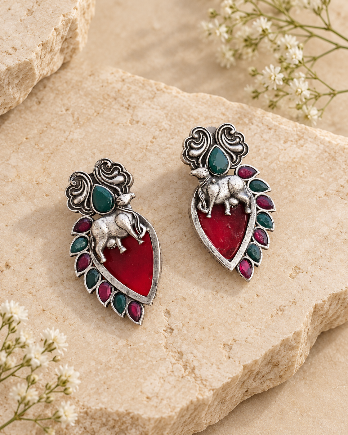 Red Nandi silver lookalike earrings with Mona Lisa stone on beige stone background