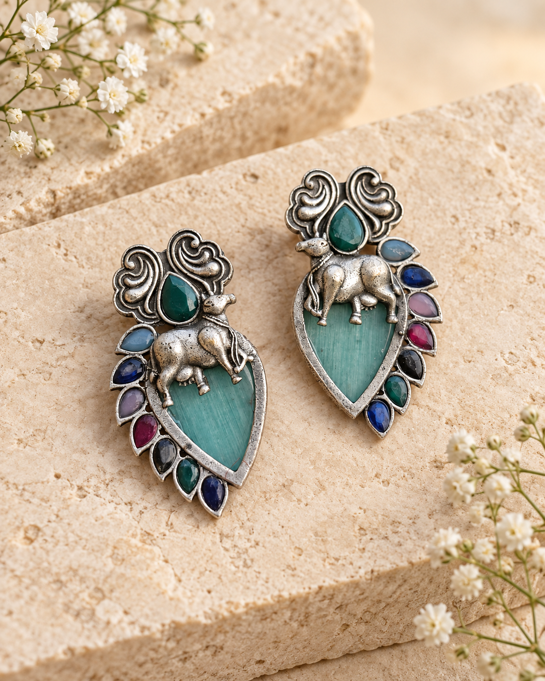 Teal Nandi silver lookalike earrings with Mona Lisa stone on beige stone background