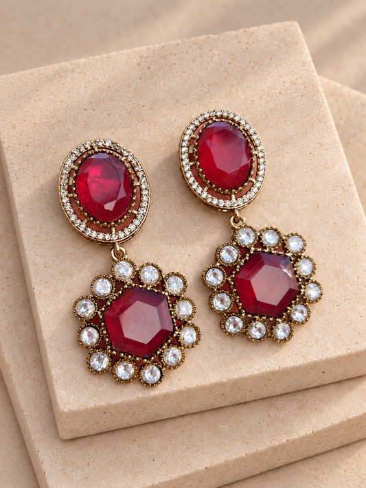 Noor red oval and hexagonal drop earrings with clear-stone borders on beige square stones.