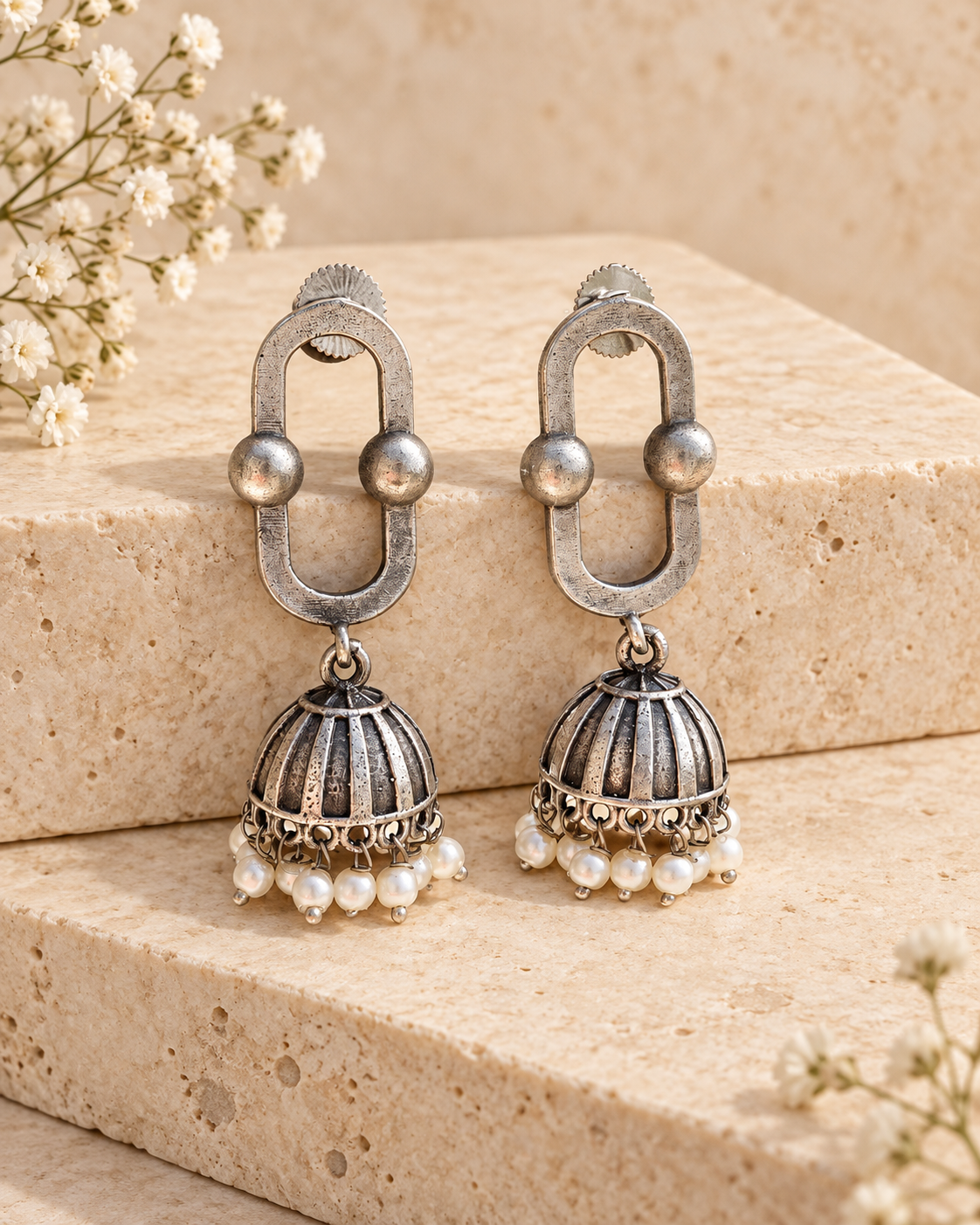 Oval link oxidized silver lookalike jhumka earrings on beige stone background