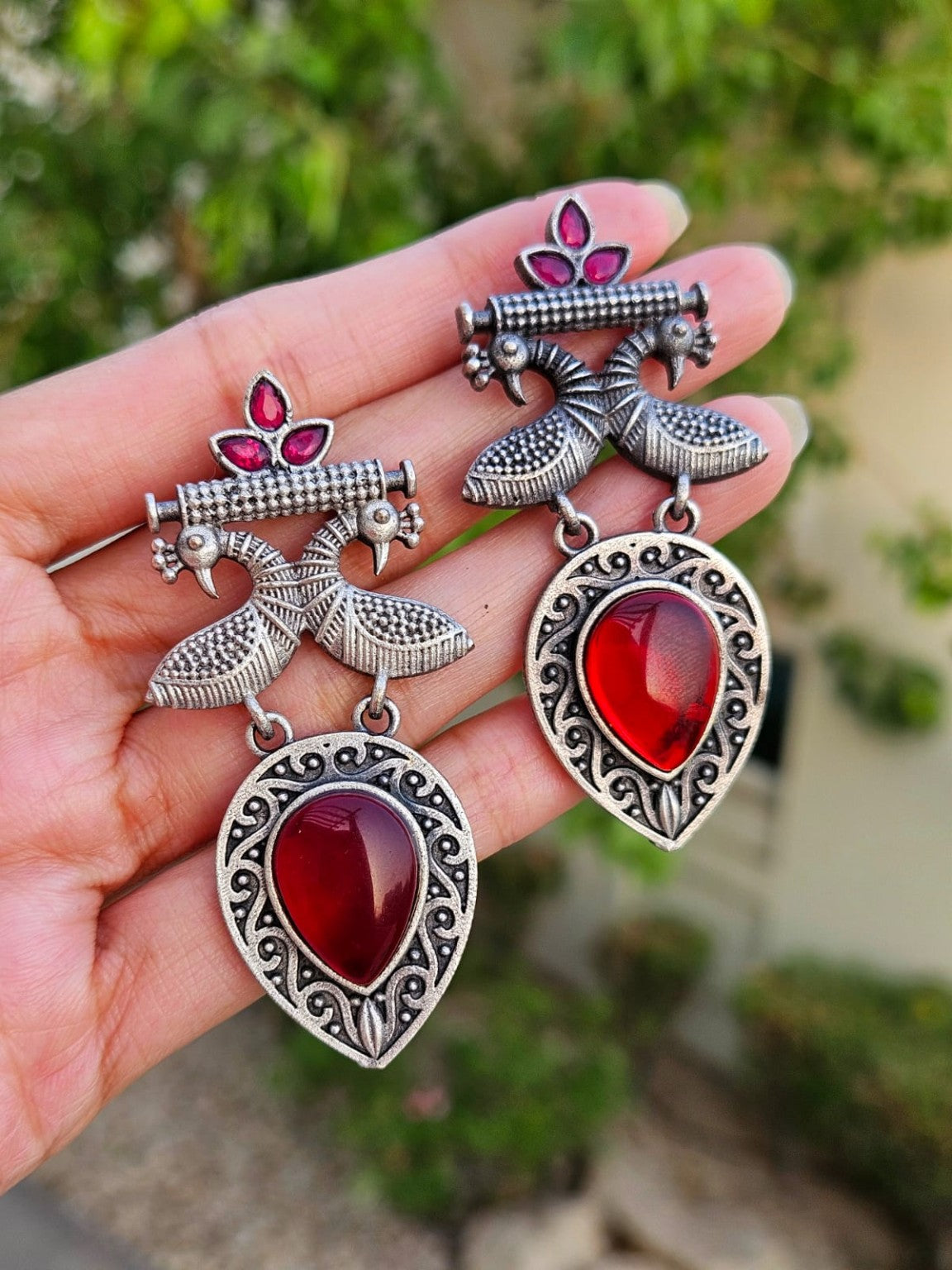 Red peacock Mona Lisa stone earrings in natural daylight