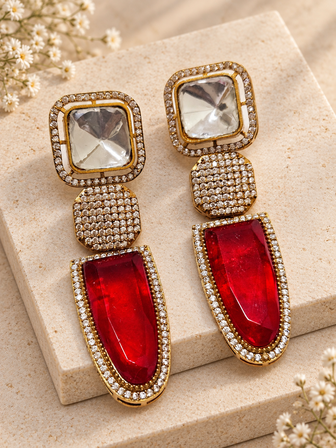 Red doublet dangler earrings with clear square tops and crystal-set middle links on beige square stones.
