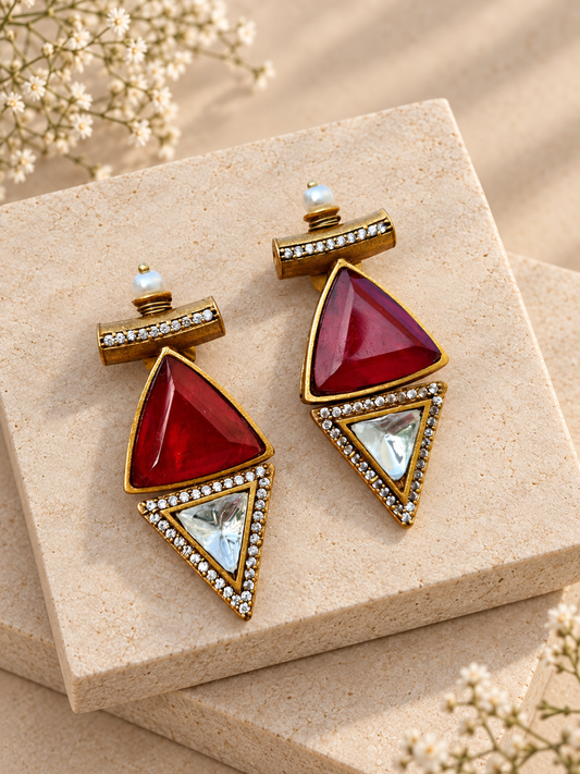 Antique gold-tone earrings with red triangles, clear inverted triangles and pearl tops on beige square stones.