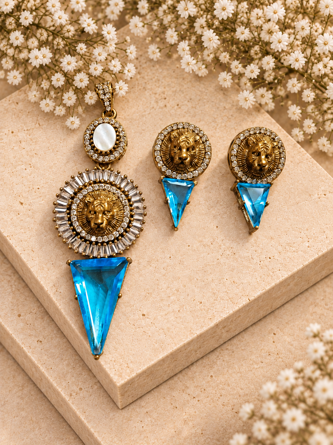 Sabya Inspired Tiger Head Pendant Set, Blue colour, on beige square stone with small white flowers.