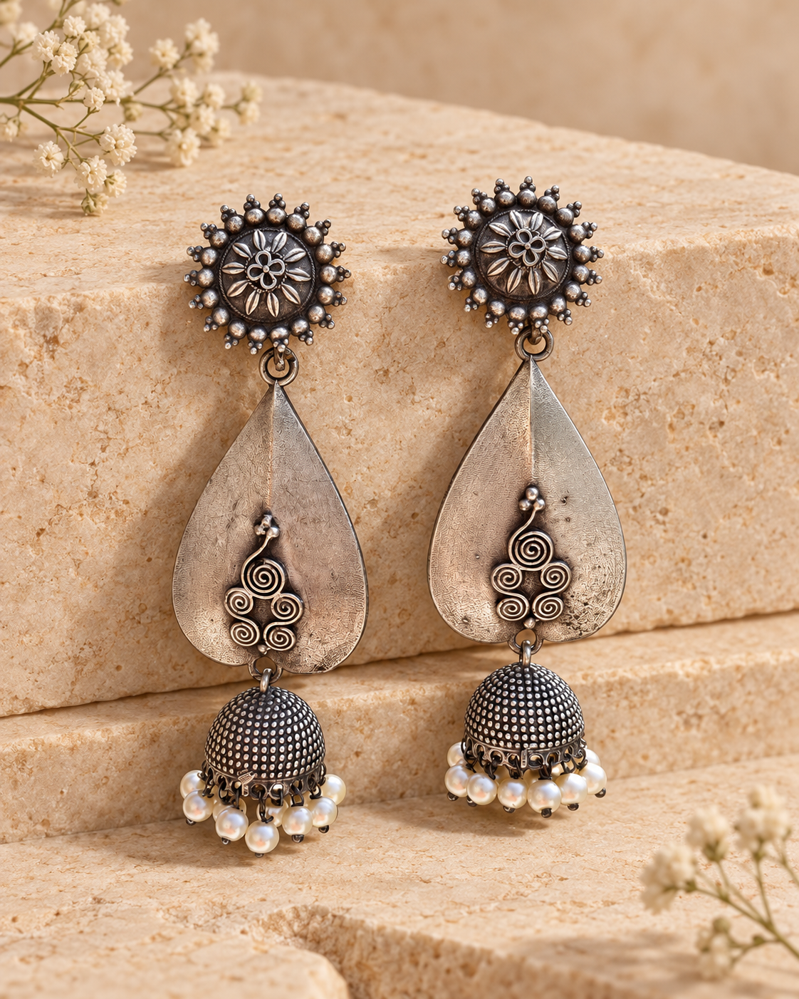 Teardrop oxidized silver lookalike jhumka earrings on beige stone background